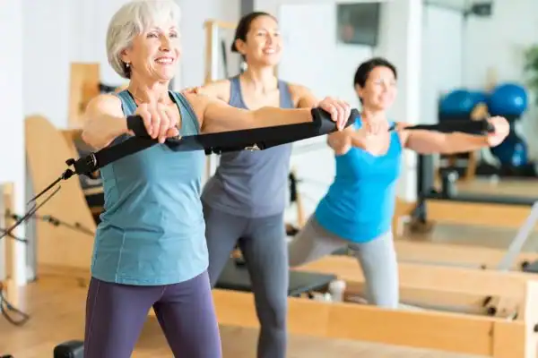 Toning Arms After 60: Empowering Womens Fitness Through Effective Weight Training 2 older woman doing weight training Smethwick and resistance in the gym to tone upper arms